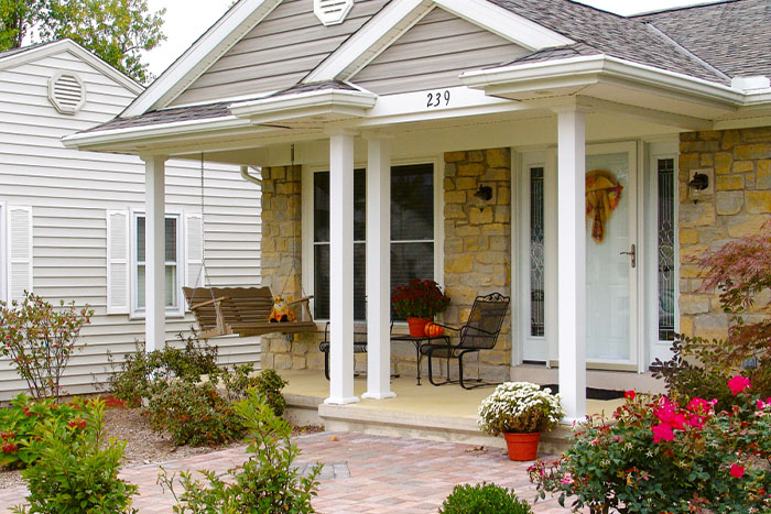 Sweet front porch surrounded by gardens with decorative white columns